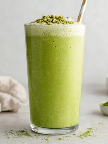 Banana matcha smoothie served in a glass on a white kitchen counter