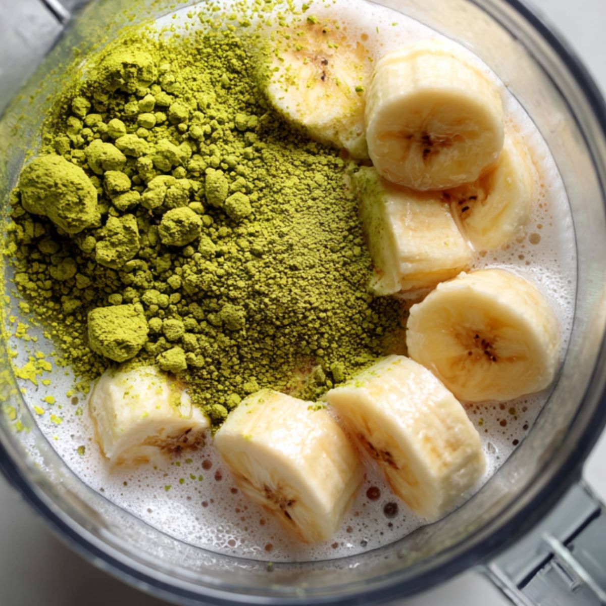 Blender filled with banana, matcha powder, and almond milk