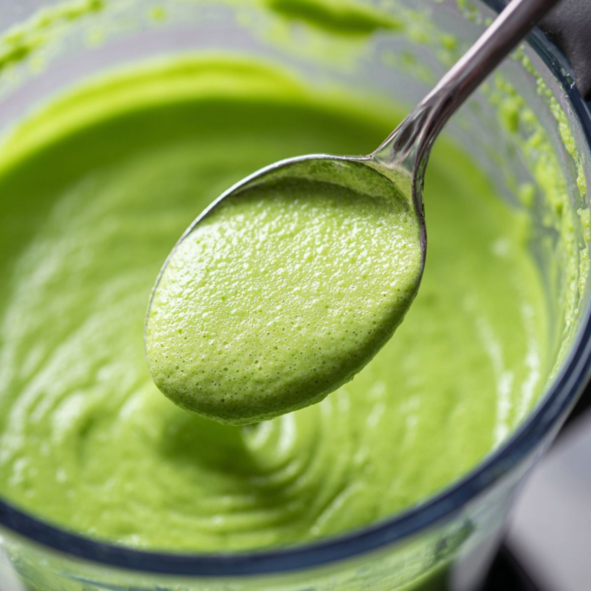 Blender being opened and smoothie checked with a spoon