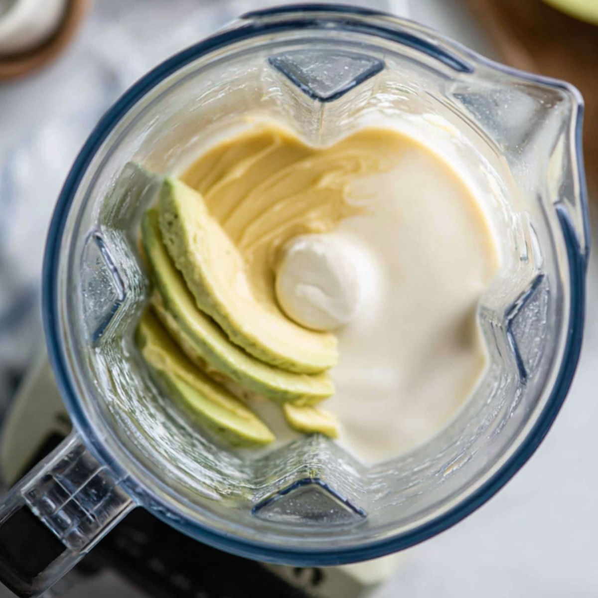 Blender filled with avocado, milk, and condensed milk ready to mix