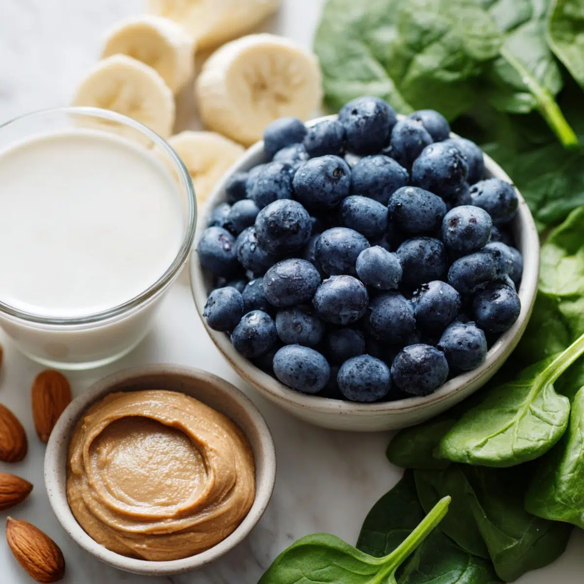 Ingredients for a healthy blueberry smoothie laid out on a white counter from above
