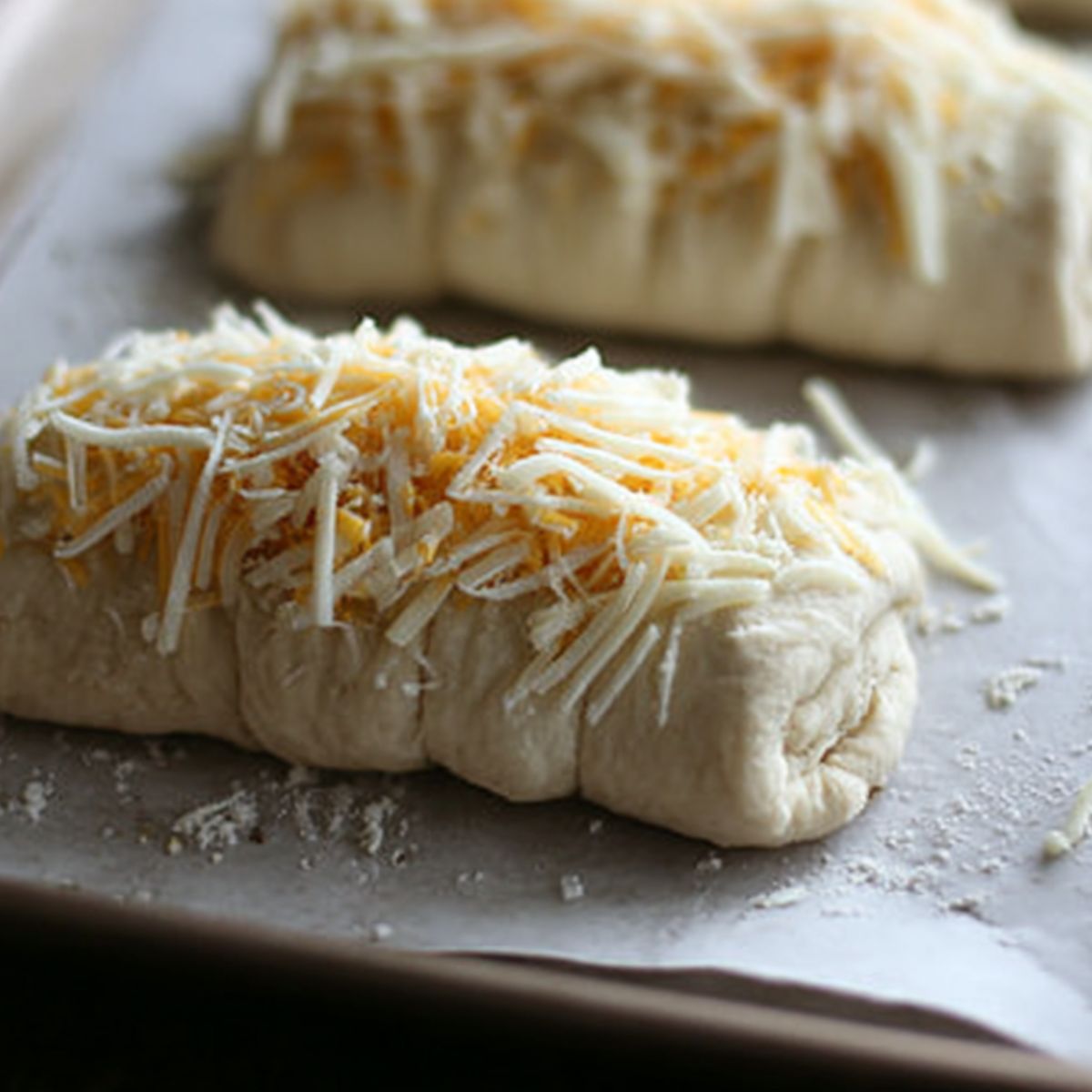 Brushing melted butter on stuffed cheesy bread before baking