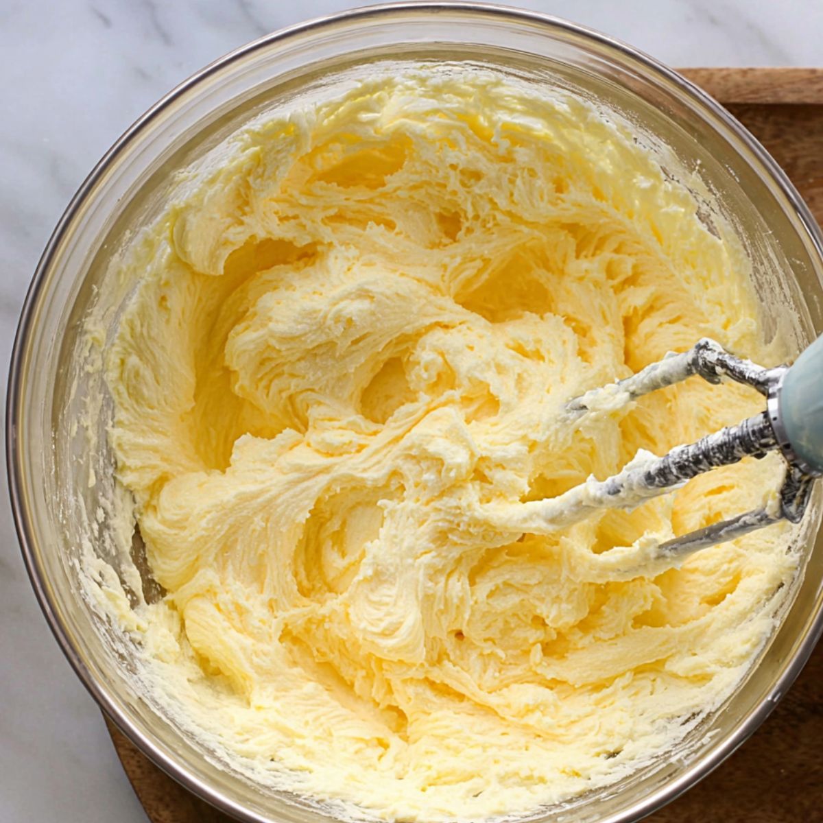Butter and sugar being creamed together in a mixing bowl with a hand mixer