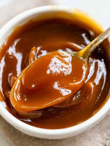 Spoon dripping homemade date Date Caramels onto white plate on kitchen counter