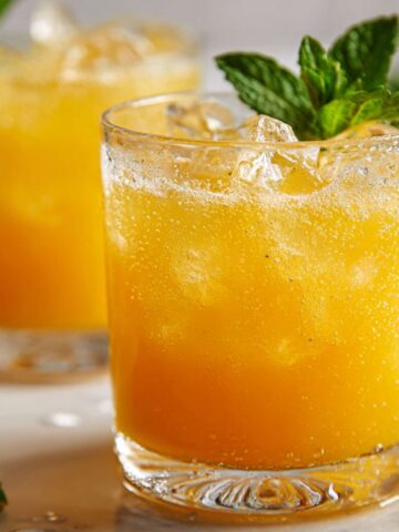 A glass of sugar free orange juice on a white countertop