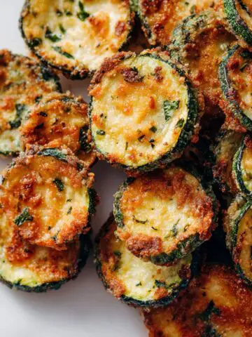 Crispy homemade zucchini chips on a white counter from above