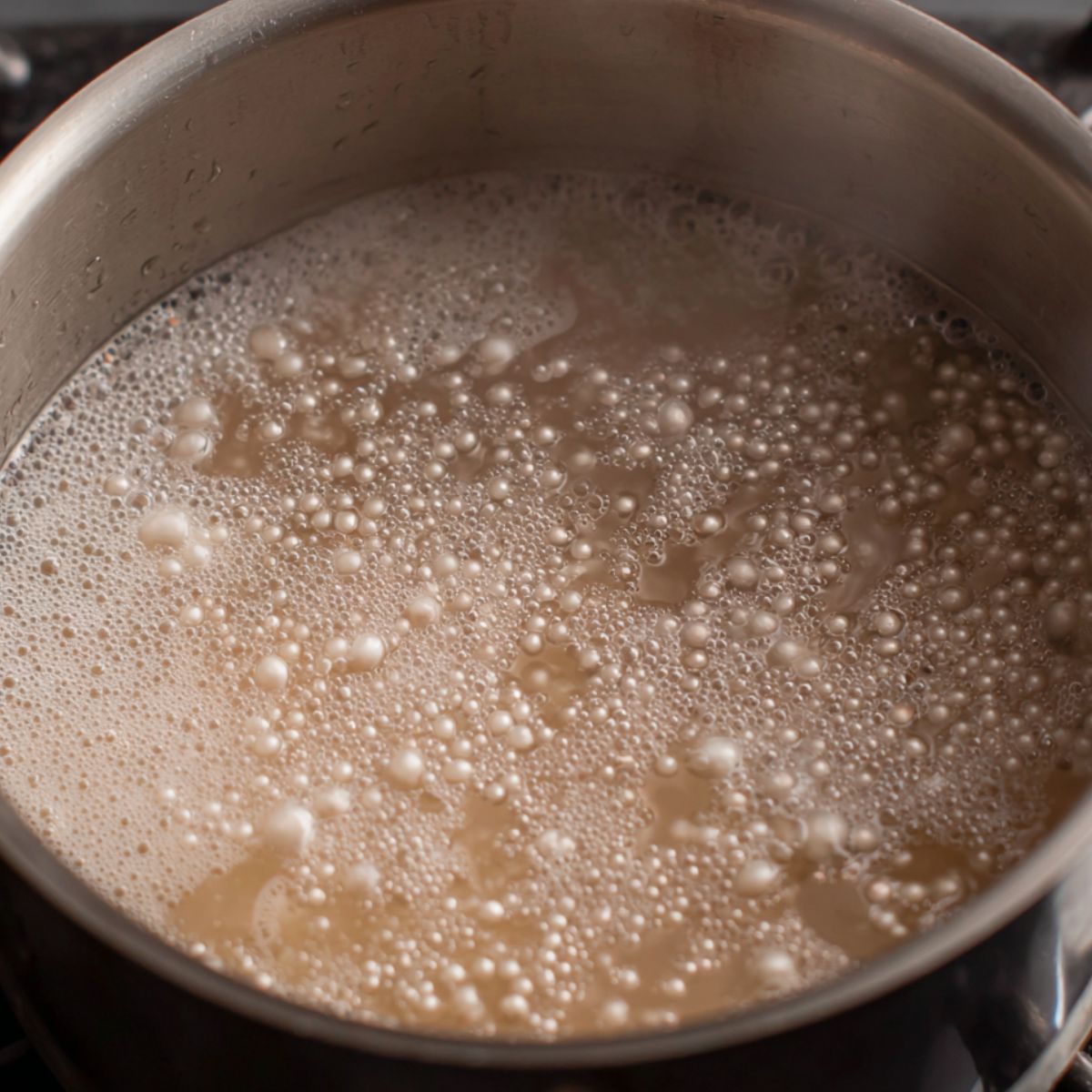 Sago pearls boiling in a pot on a white kitchen counter