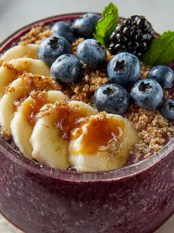 Alt Text: Best acai bowl topped with fresh fruit and granola on a white kitchen counter