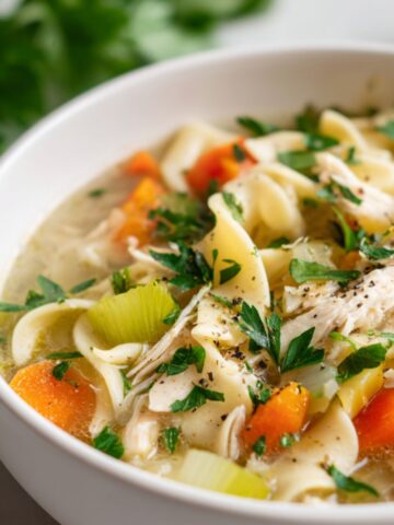 Homemade gluten-free chicken noodle soup served in a ceramic bowl on a white kitchen counter