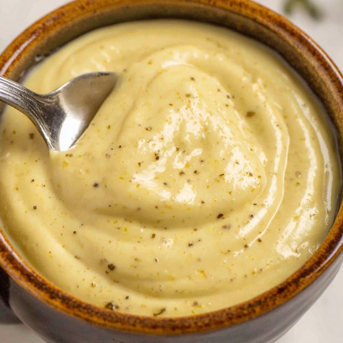 Small bowl with mayo, lemon juice, and mustard being whisked with a spoon