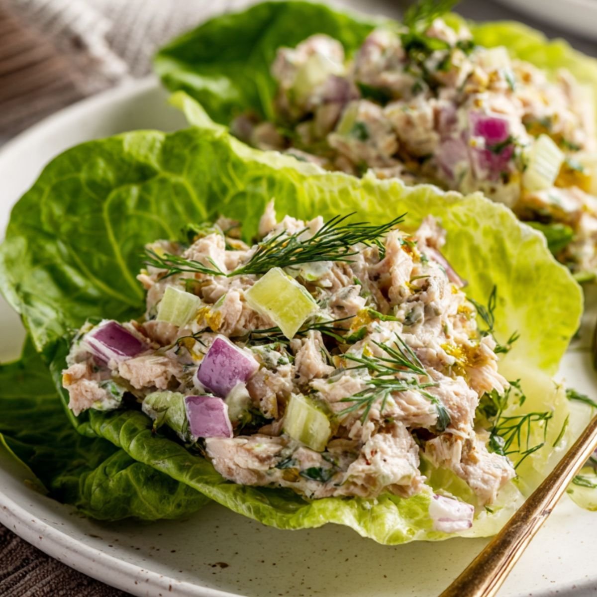 Finished keto tuna salad served on lettuce leaves with a spoon on the side