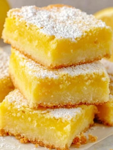 Two ingredient lemon bars cut into imperfect squares on parchment paper