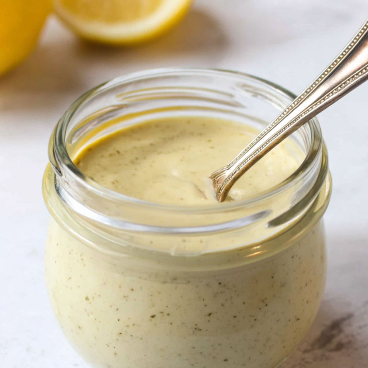 Caesar dressing in a bowl with fresh ingredients around