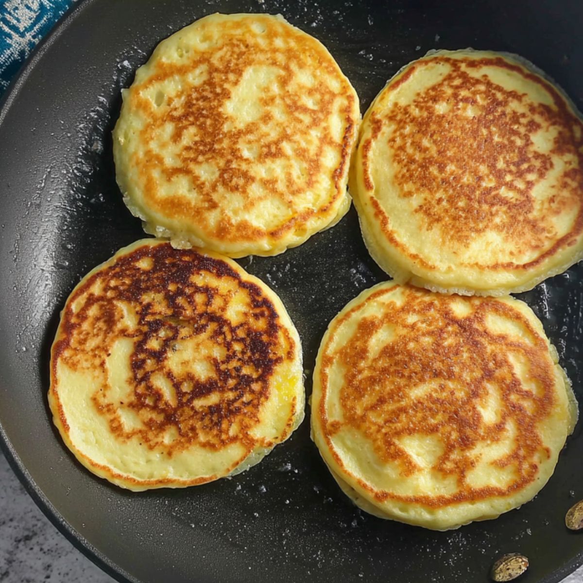Mango pancakes cooking on a skillet over medium heat.