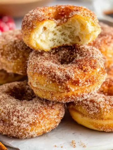 Homemade mini donuts sprinkled with cinnamon sugar on white counter