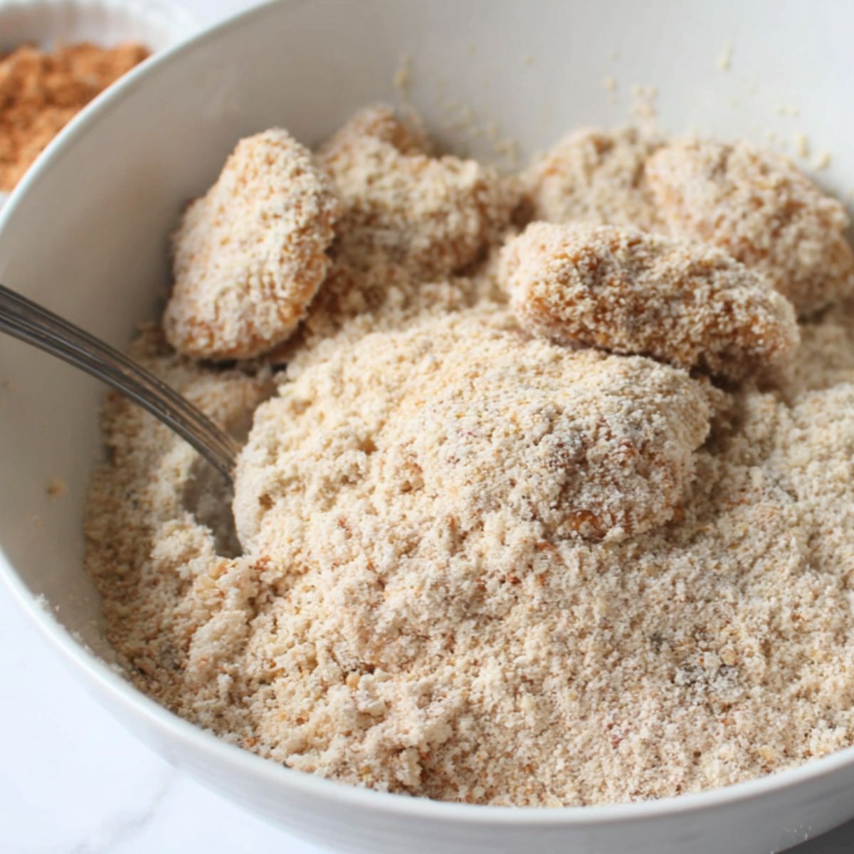 Nugget being breaded in flour, egg, and panko.