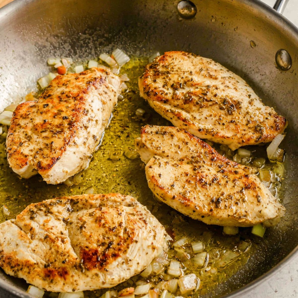Chicken searing in a pot with vegetables prepped nearby on the counter