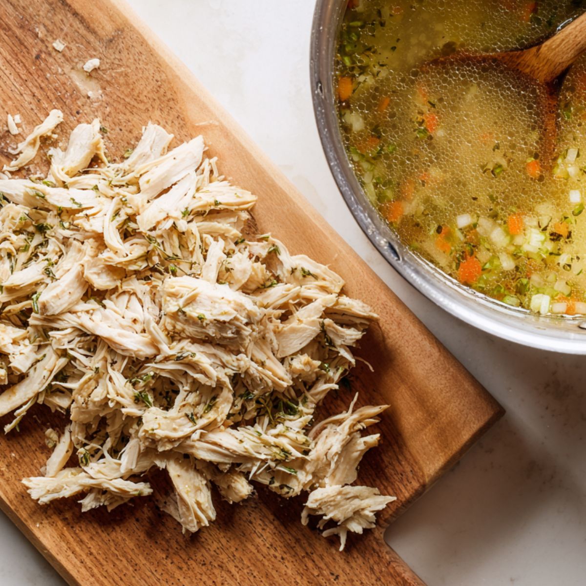 Shredded chicken being added back into a flavorful homemade soup
