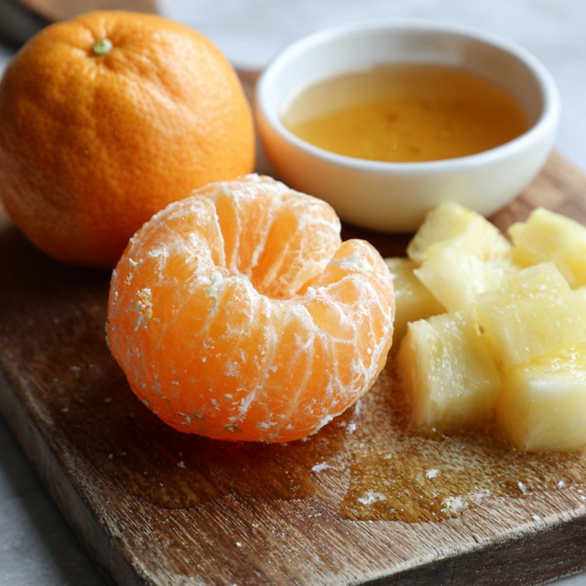 Cut pineapple and peeled orange ready on a cutting board