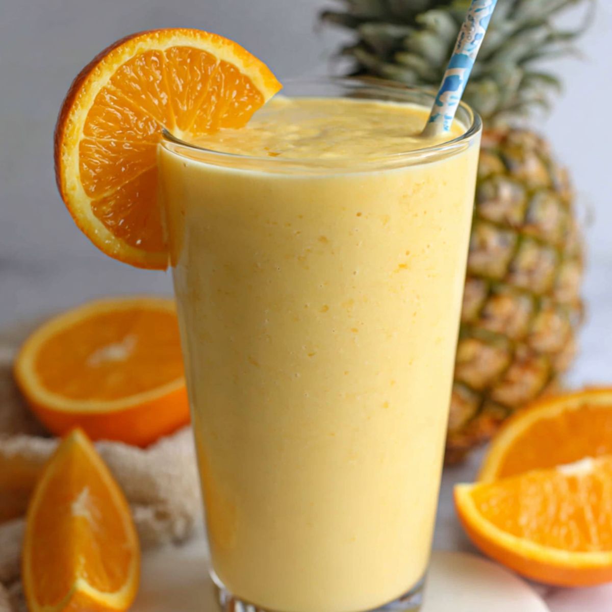 Pineapple orange smoothies served with garnish on a kitchen counter