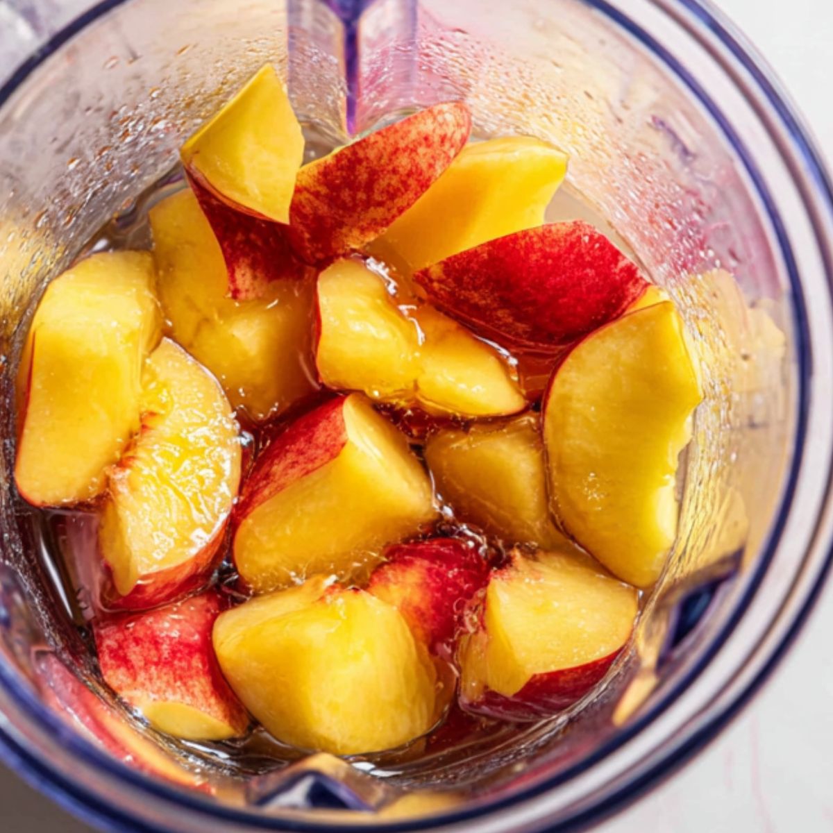 Blender with fresh peach chunks for lemonade preparation