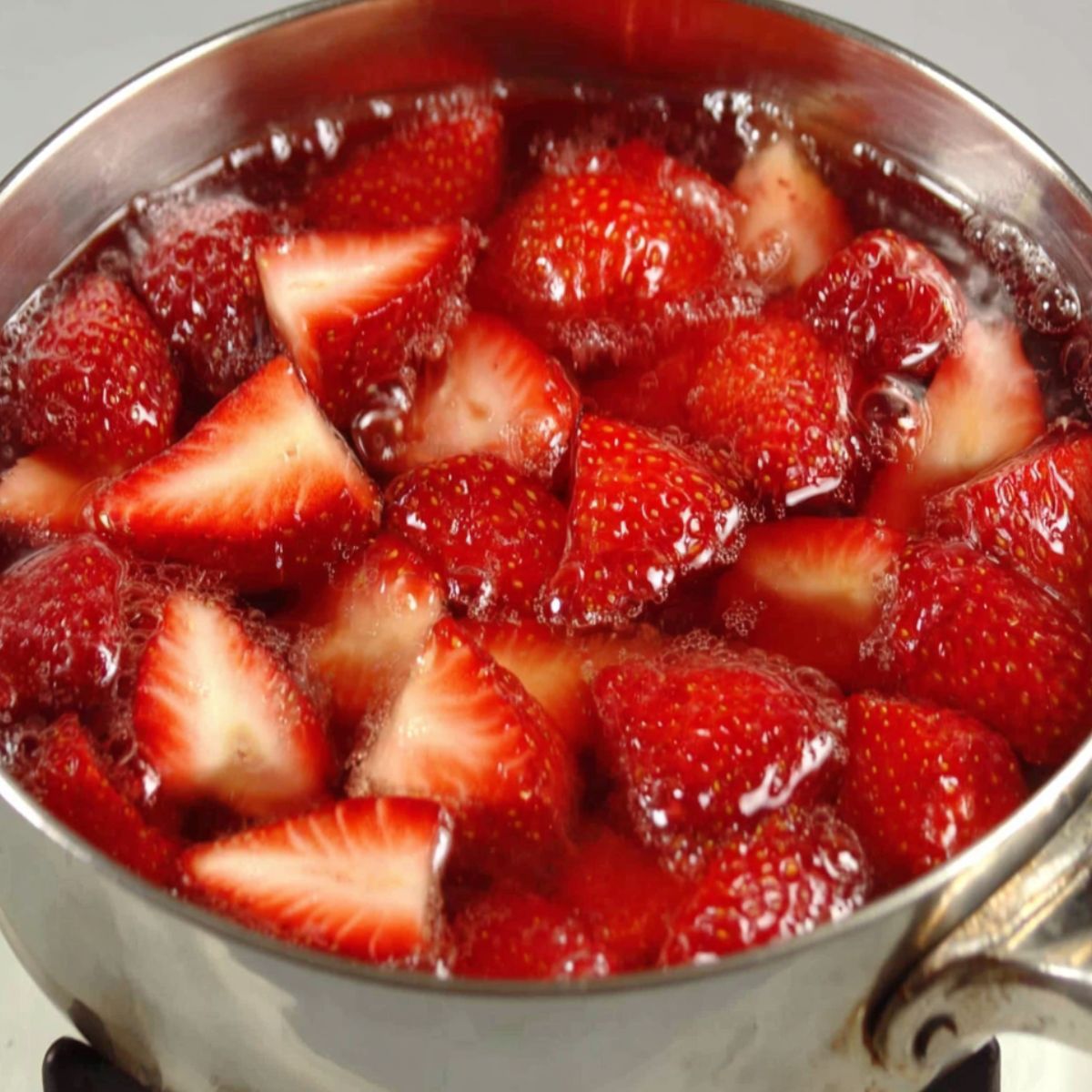 Strawberries simmering in a small pot to make syrup for strawberry sweet tea