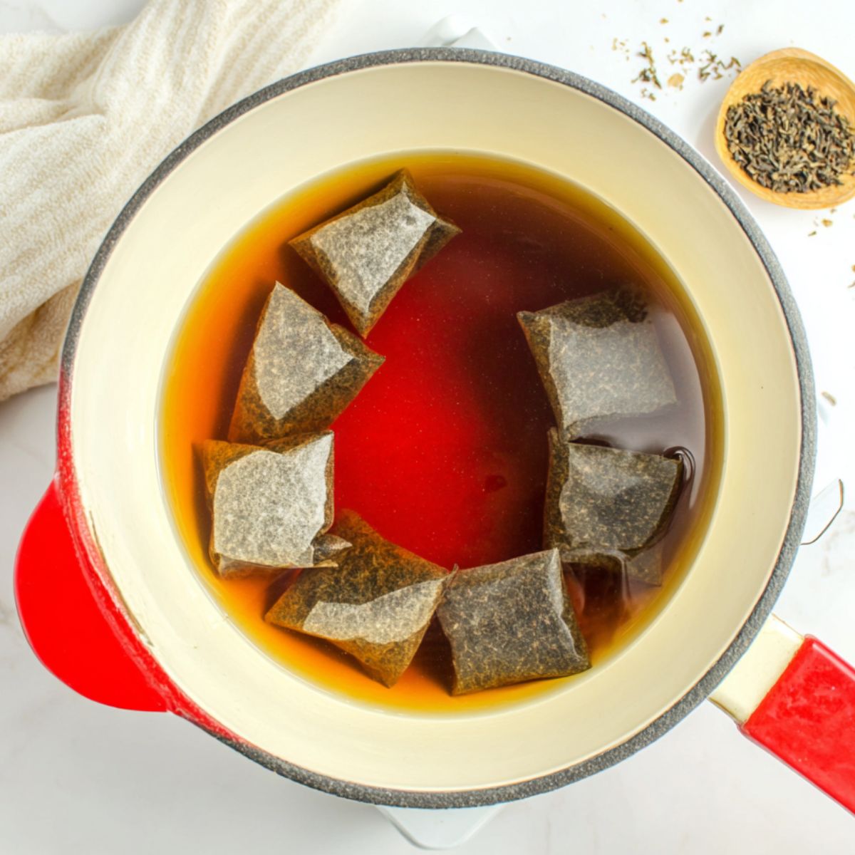 Loose black tea steeping in a pot of hot water with sugar dissolving