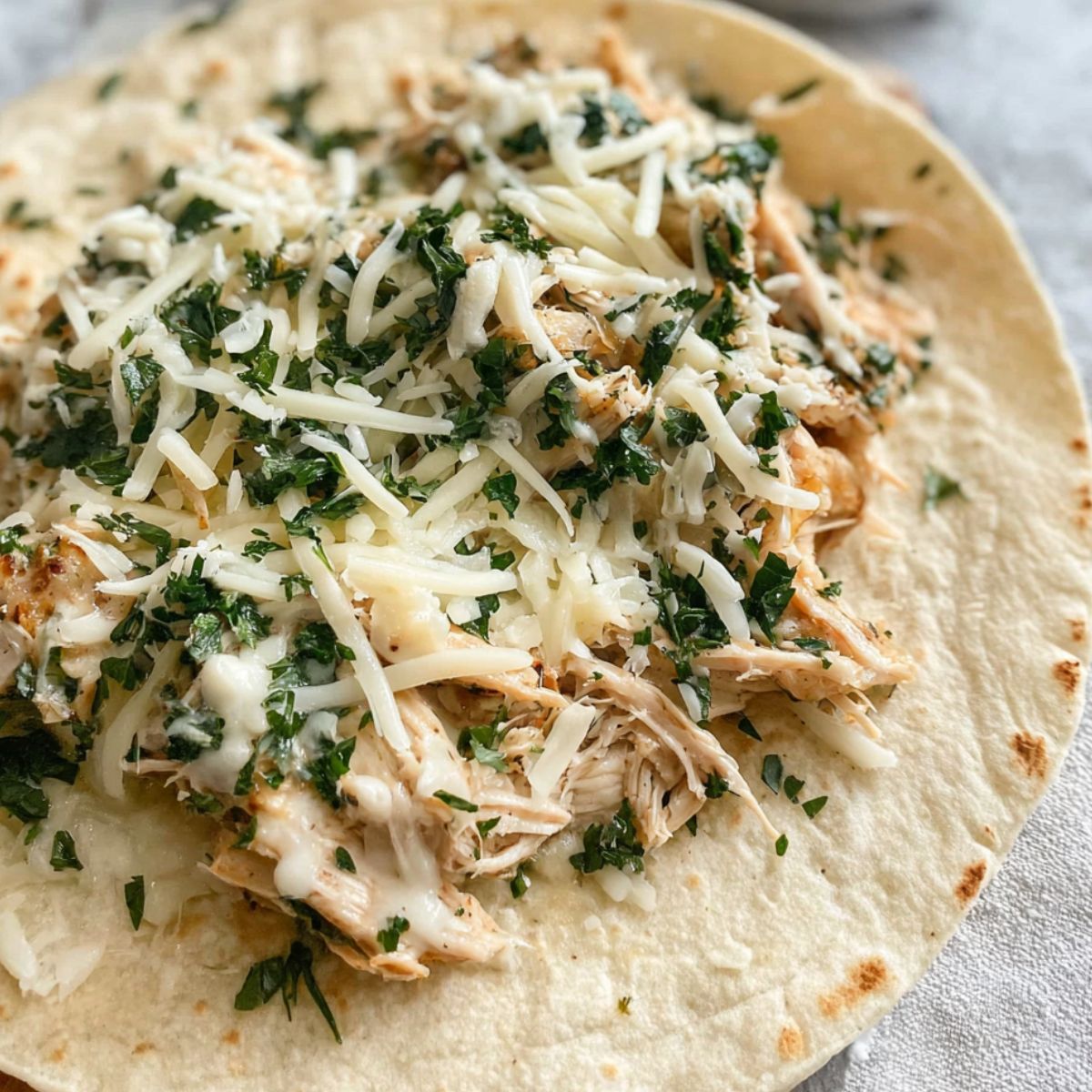 Assembling the wrap with chicken, garlic sauce, and cheese