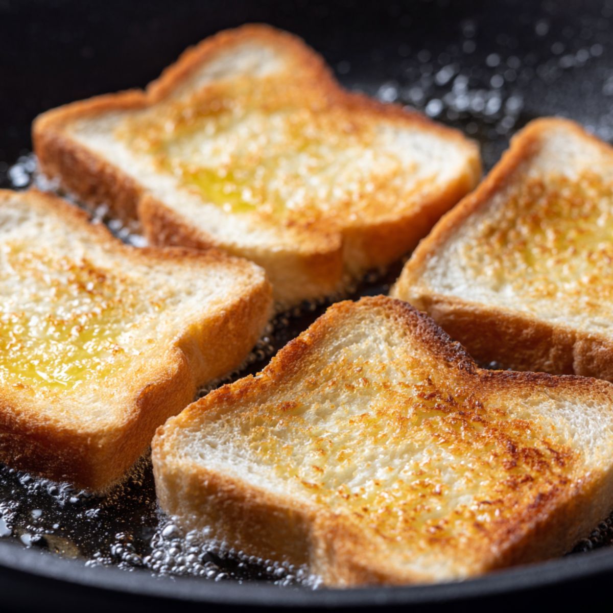 Bread slices toasting in a pan with butter