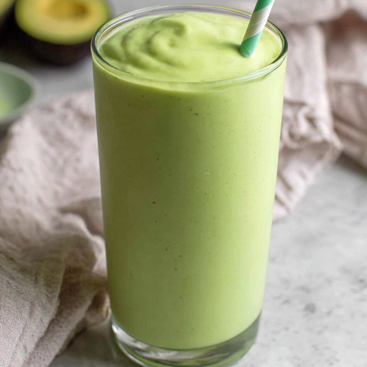 Vietnamese avocado smoothie in a tall glass with avocado peels nearby