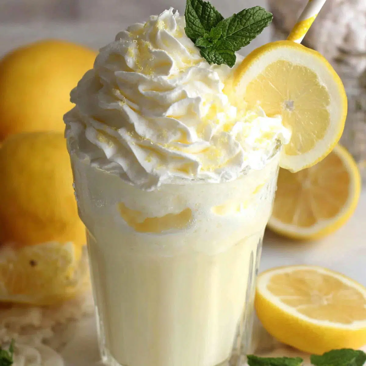 Overhead shot of whipped lemonade served in a glass with fluffy top, lemon slice, and mint on a white counter