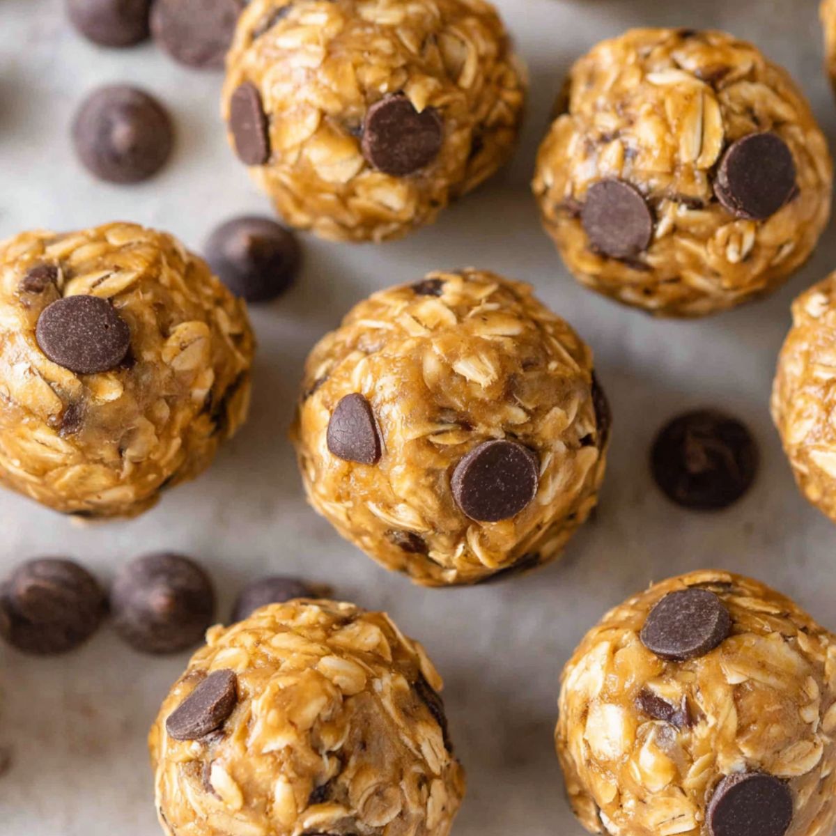 Rolling oatmeal peanut butter protein balls by hand on a white counter.