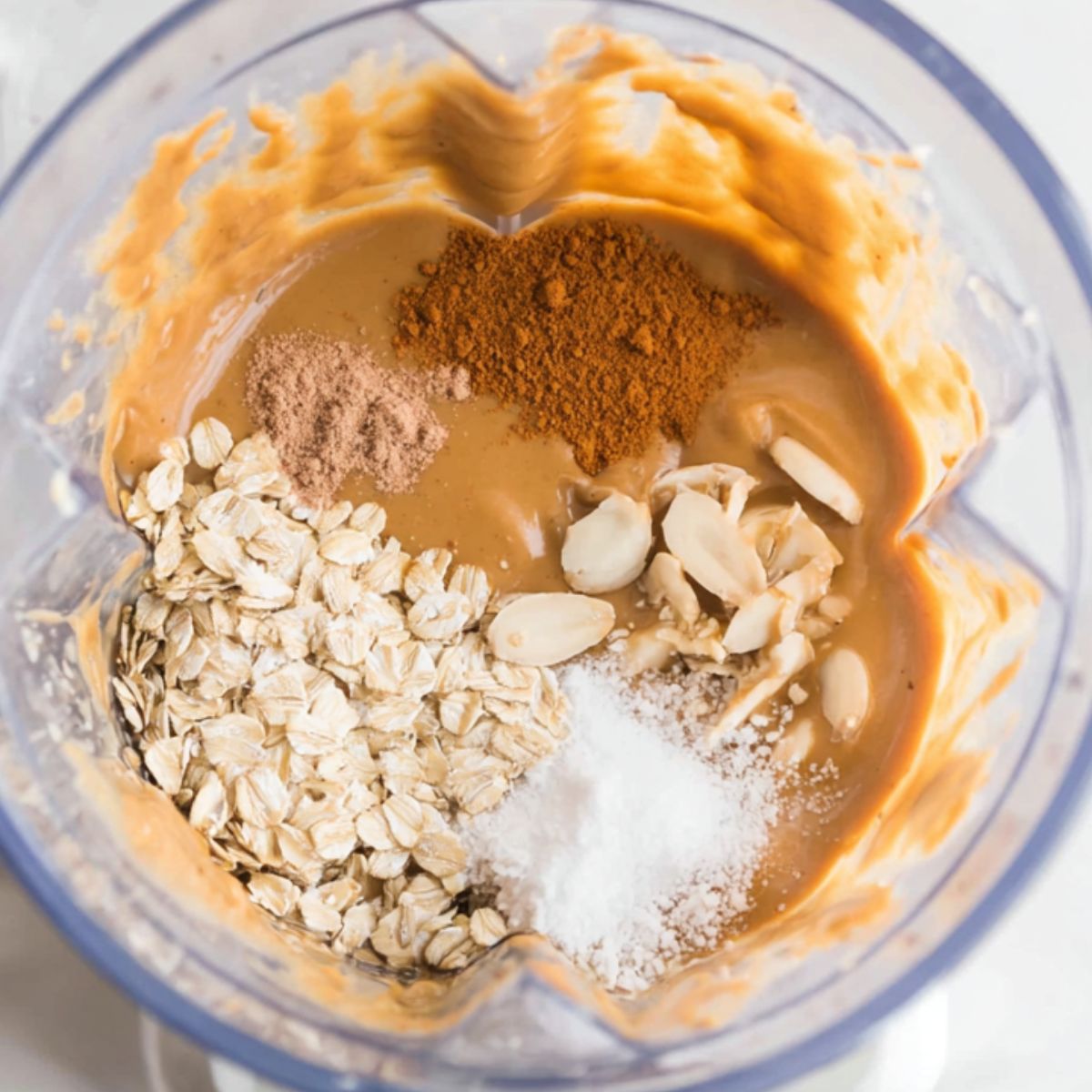 Adding peanut butter, cinnamon, and ice to the blender for the best banana protein shake.