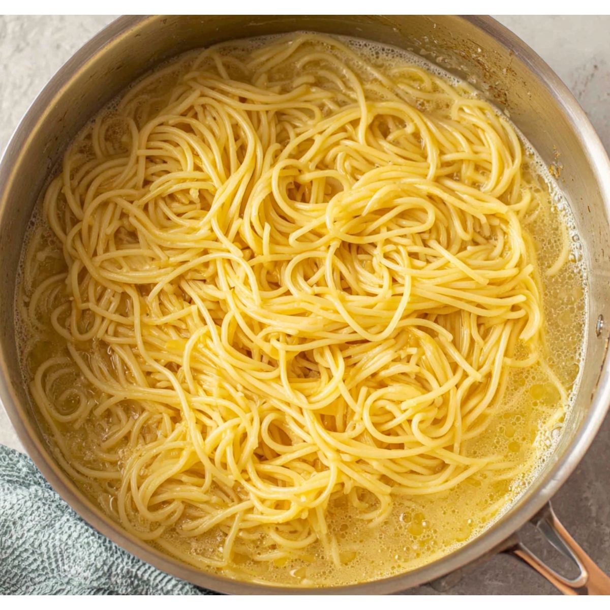 Spaghetti boiling with an egg and cheese mixture prepared beside it