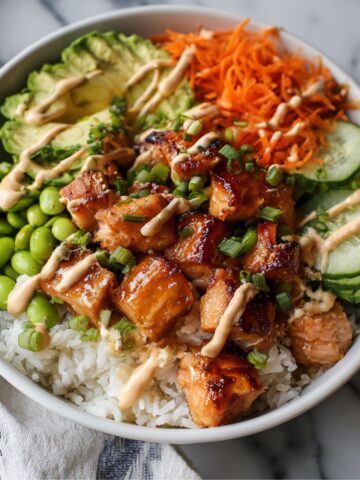 Homemade salmon bowl with rice, vegetables, and sriracha mayo