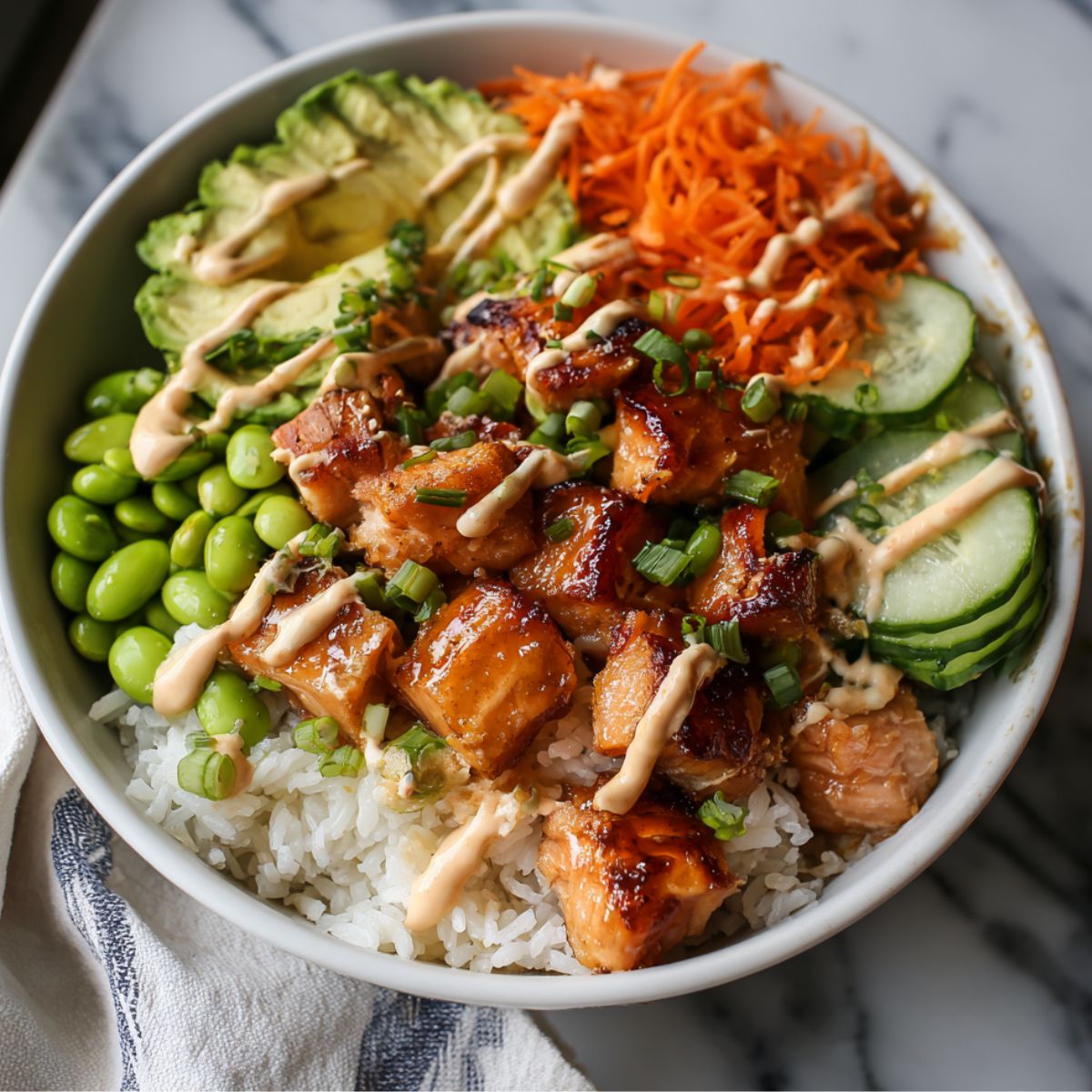 Homemade salmon bowl with rice, vegetables, and sriracha mayo