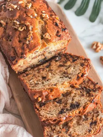 Homemade Greek yogurt banana bread sliced on a white kitchen counter with crumbs scattered.