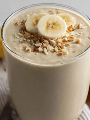 A glass of the best banana protein shake on a kitchen counter, looking creamy and h