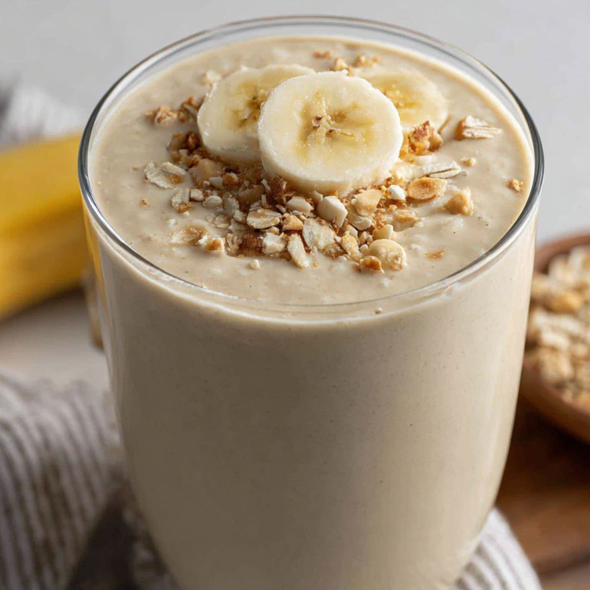 A glass of the best banana protein shake on a kitchen counter, looking creamy and homemade.