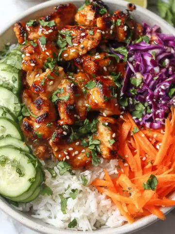 Homemade Bang Bang Chicken Bowl with crispy chicken, rice, and fresh vegetables on a white kitchen counter.