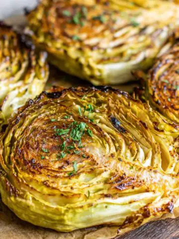 Homemade roasted cabbage steaks on a baking tray with golden edges, shot from above.