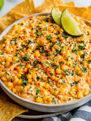 Homemade Mexican street corn dip topped with cheese and cilantro, served with tortilla chips.