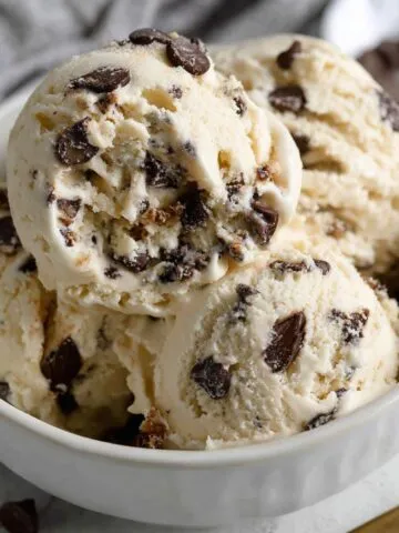 Homemade chocolate chip ice cream served in a white bowl on a kitchen counter.