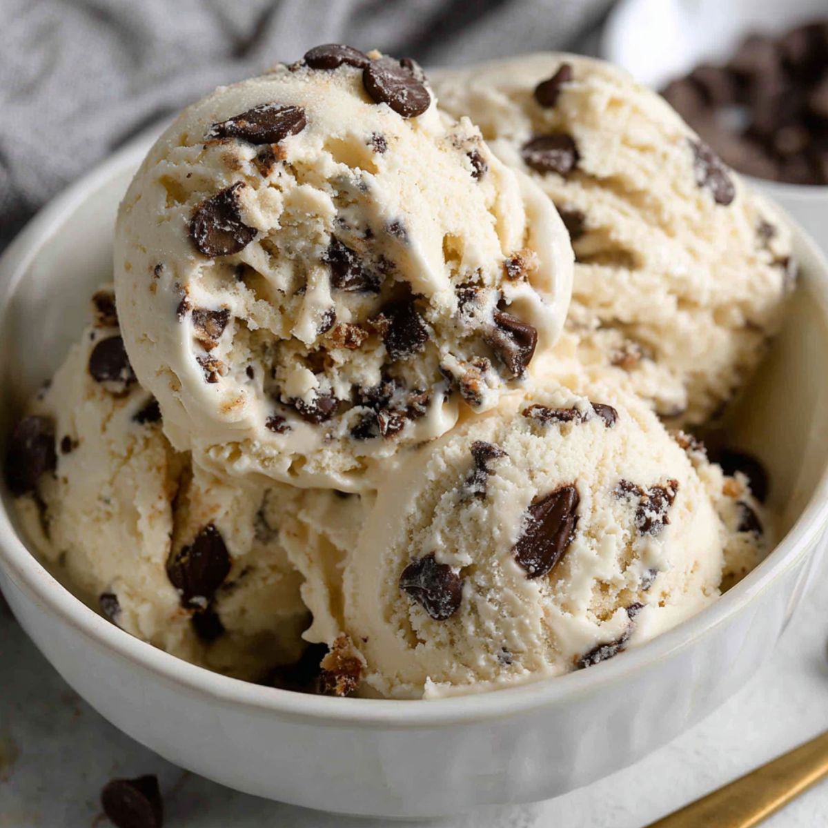 Homemade chocolate chip ice cream served in a white bowl on a kitchen counter.