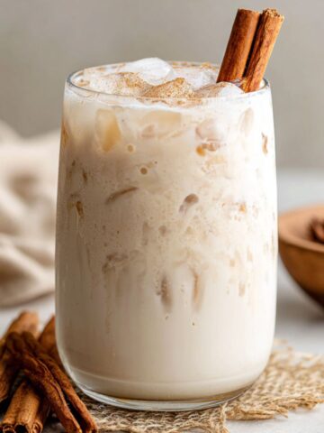 Homemade healthy horchata recipe served with ice and cinnamon on a white kitchen counter, top-down view.