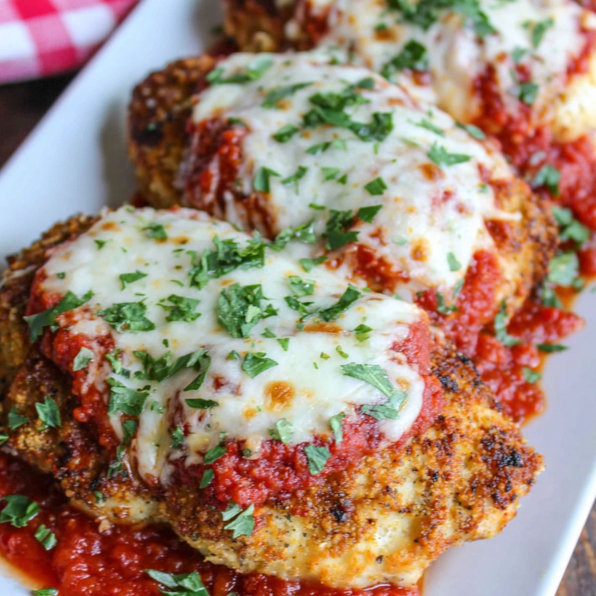 Homemade keto chicken parmesan on a white counter with melted mozzarella and marinara sauce, photographed from above.