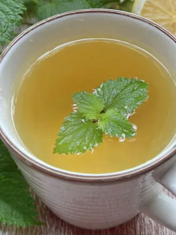 A homemade cup of lemon balm tea recipe on a white kitchen counter, viewed from above.