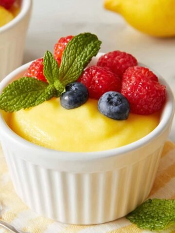 Glass bowl of creamy homemade lemon curd dessert recipe on a white kitchen counter