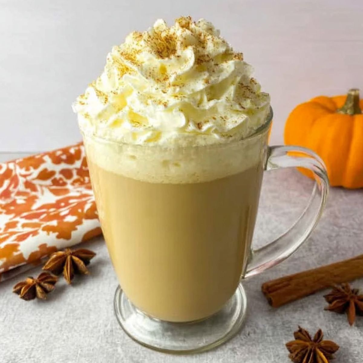 homemade pumpkin spice latte with whipped cream and cinnamon on a white kitchen counter.