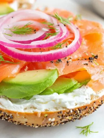 Homemade salmon cream cheese bagel on a white kitchen counter, photographed from above.